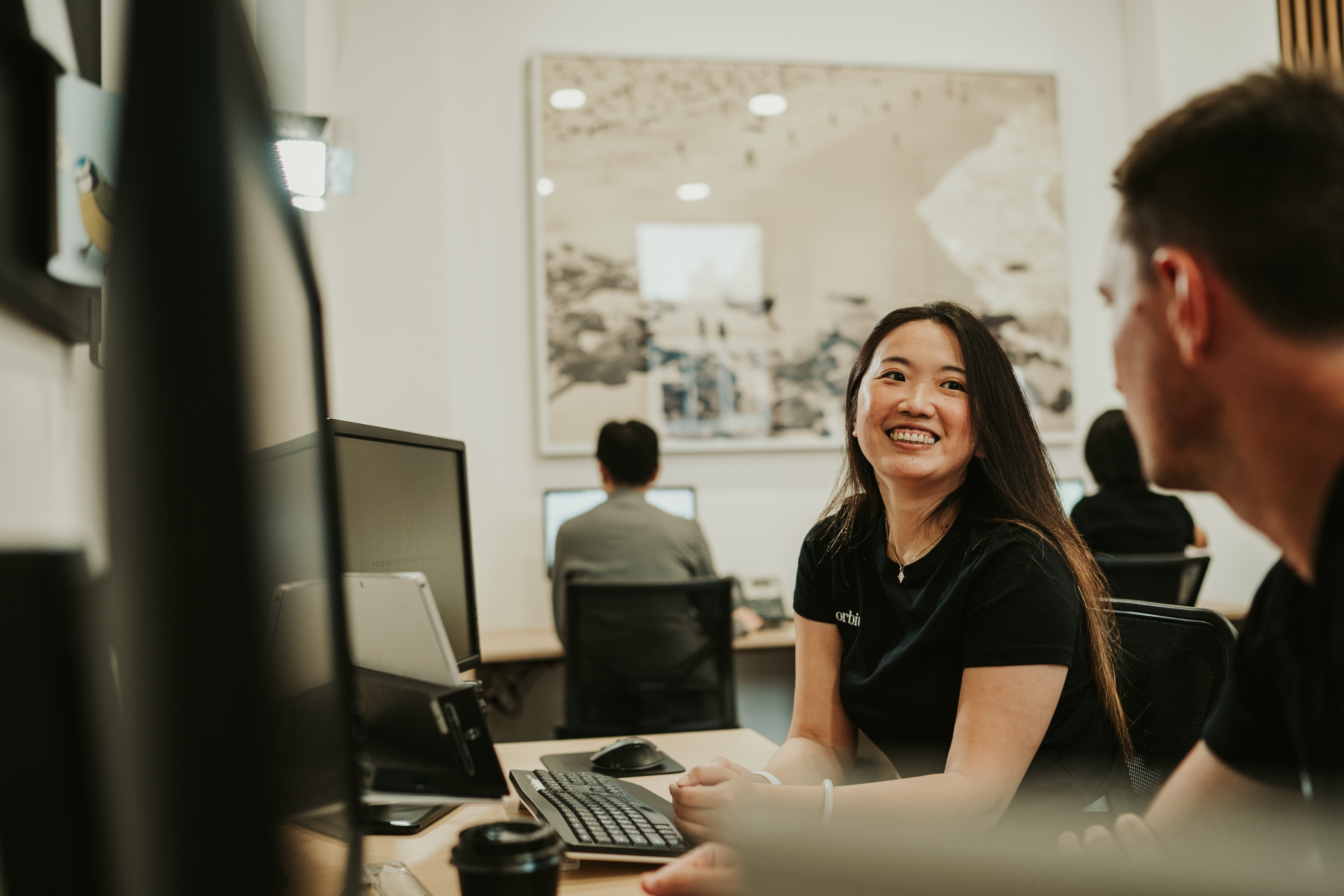 Smiling Orbit Team Member Seated At Desk In Sydney Office