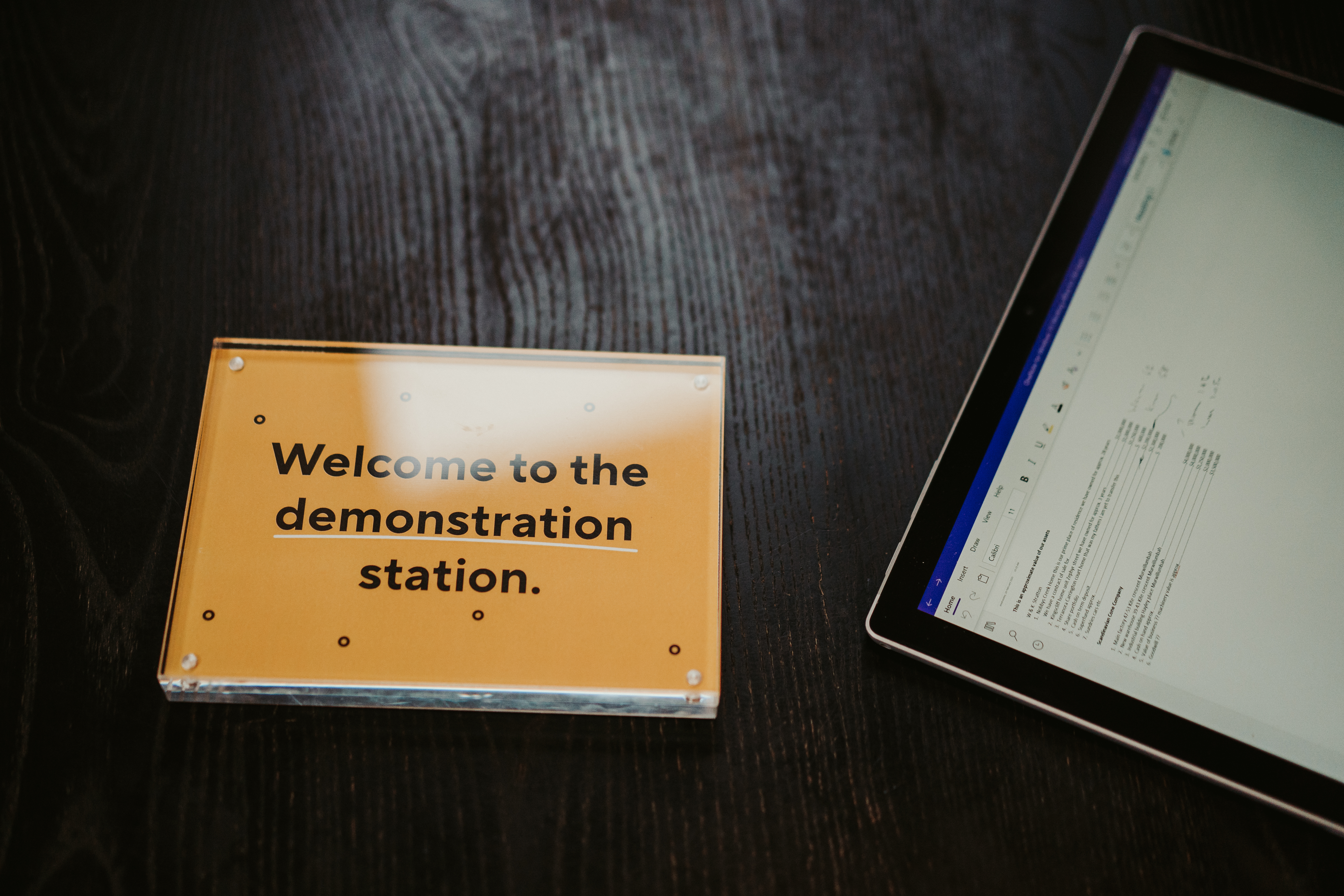 Sign Reading ‘welcome To The Demonstration Station’ Next To Ipad On The Table In Sydney Office